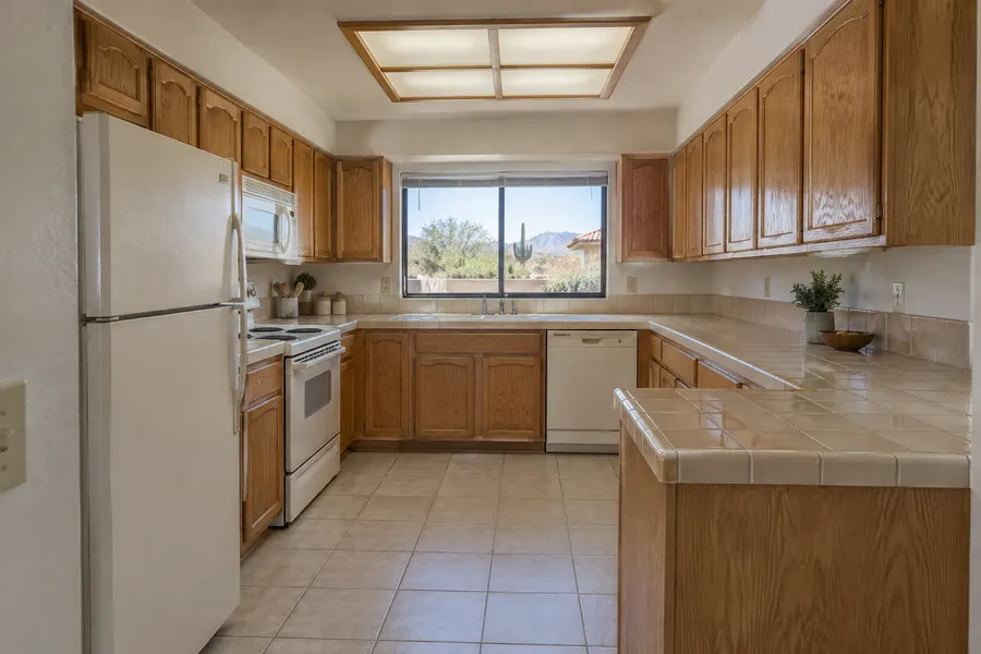 Dated 1990s kitchen with oak cabinets and tile counters